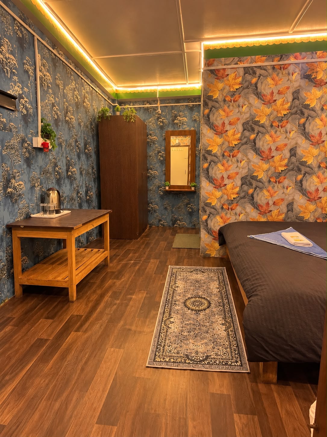 Kanchenjunga Suite — wallpapered room with a king bed, wooden tea table, wardrobe and mirror