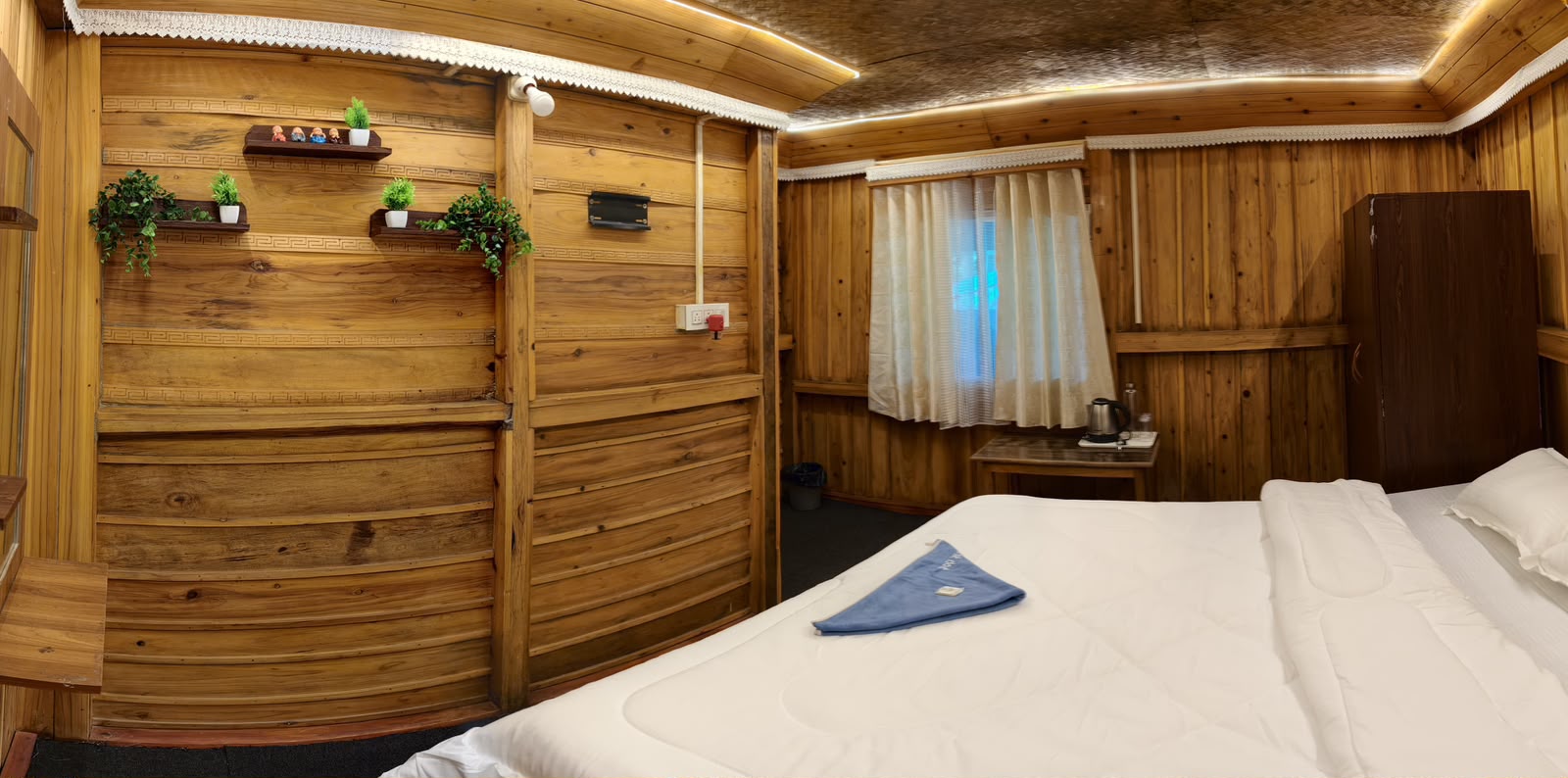 Cedar Nest — wood-panelled bedroom with potted plants on wooden shelves and a curtained window