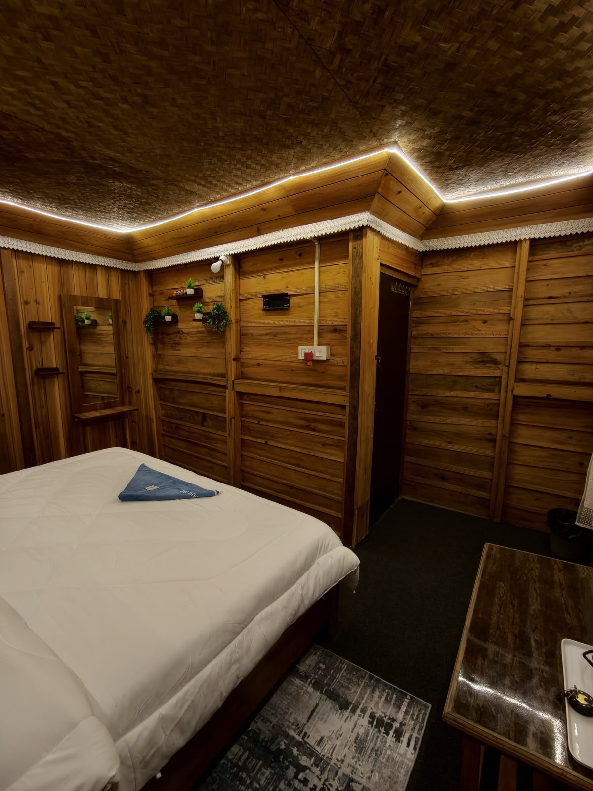 Cedar Nest — wood-panelled corner with mirror and shelving beneath the woven ceiling