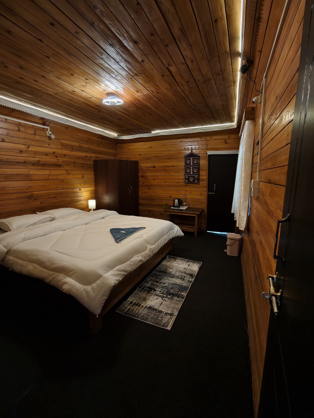 Pine Nest — wood-panelled bedroom with a double bed and dark wooden wardrobe