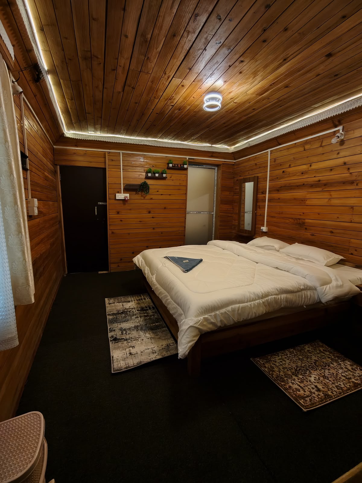 Pine Nest — wood-panelled bedroom with mirror and warm ambient lighting